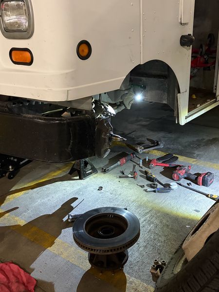 Step van front brake job at night with the old rotor and tools laid out