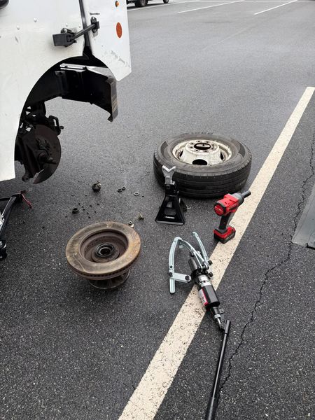 Truck wheel hub job in a parking lot with the old rotor, puller and impact gun